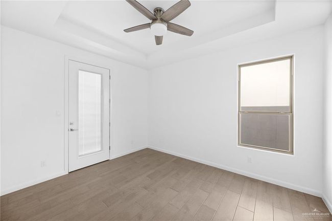 Unfurnished room with a raised ceiling, ceiling fan, and wood finished floors | Image 14