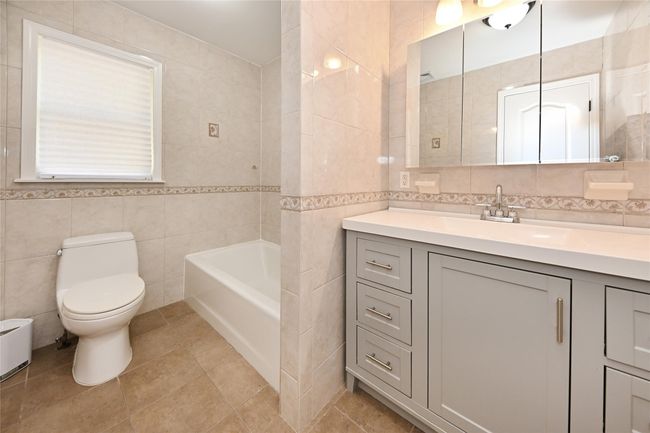 Full bath with tile walls, a bathing tub, vanity, toilet, and backsplash | Image 27
