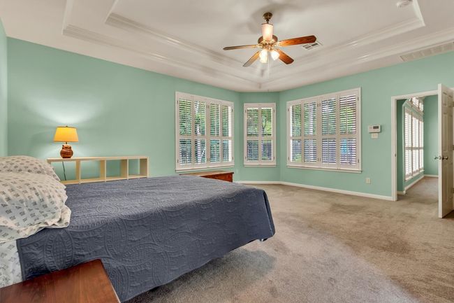 Carpeted bedroom featuring visible vents, a raised ceiling, and crown molding | Image 19