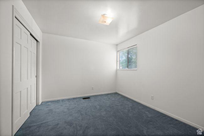 Unfurnished bedroom featuring dark carpet, a closet, and baseboards | Image 18