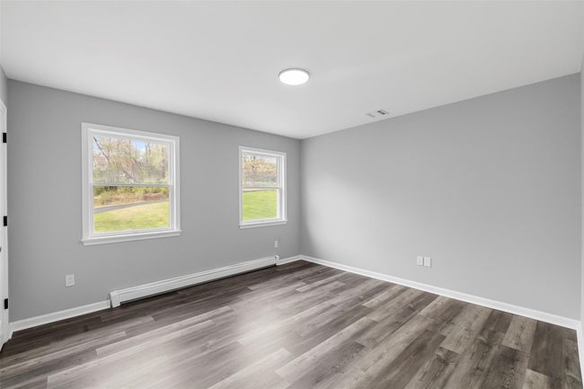 Spare room featuring a baseboard radiator, visible vents, dark wood finished floors, and baseboards | Image 15