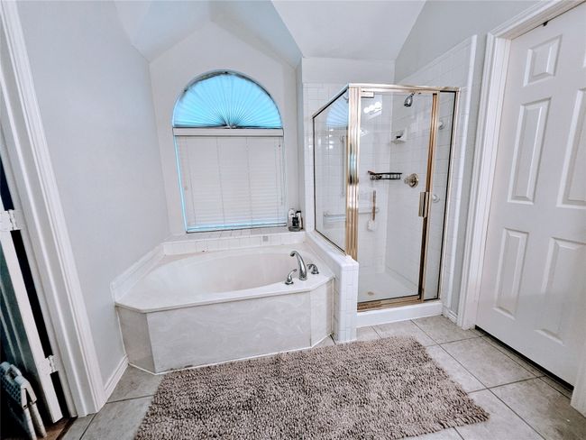 Full bathroom featuring a bath, a stall shower, tile patterned floors, and lofted ceiling | Image 24