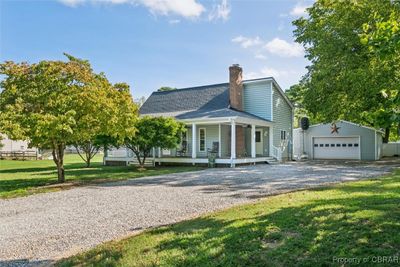 View of front of home featuring a garage, covered porch, a front lawn, and an outdoor structure | Image 1