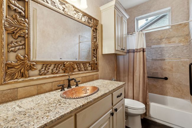 Bathroom with shower / bath combo with shower curtain, Granite countertop, copper sink, vanity, tile backsplash, and toilet | Image 19