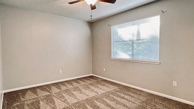 Carpeted spare room with a textured ceiling, ceiling fan, and baseboards | Image 11