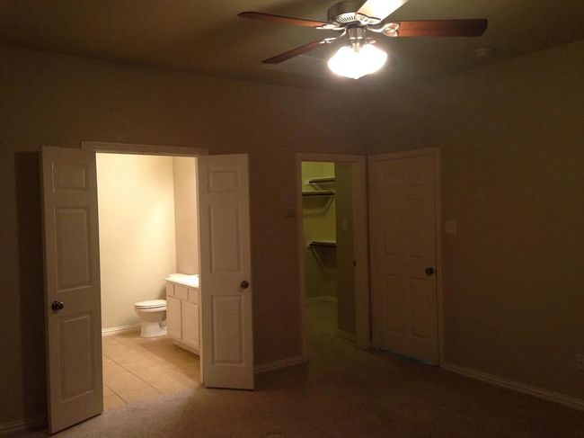 Unfurnished bedroom featuring ensuite bathroom, a walk in closet, ceiling fan, and light tile patterned floors | Image 8