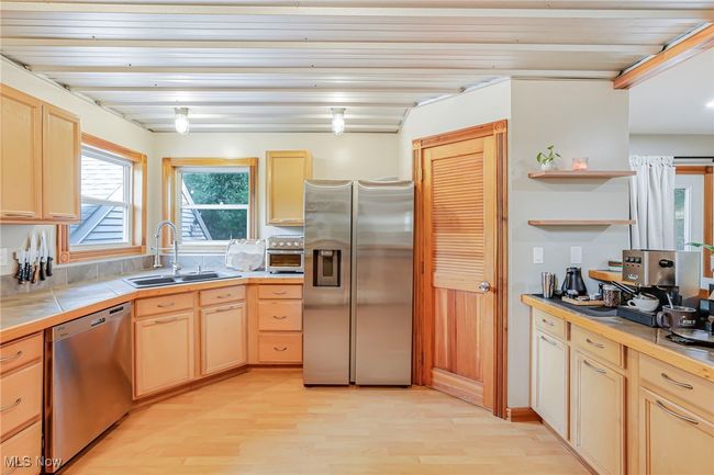 Kitchen with tile countertops, stainless steel appliances, plenty of natural light, and light wood-style floors | Image 18
