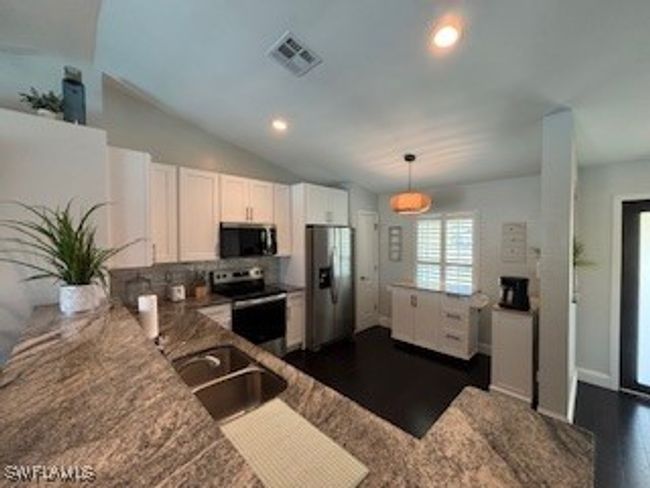 Kitchen with white cabinets, visible vents, stainless steel appliances, dark wood finished floors, and a sink | Image 5