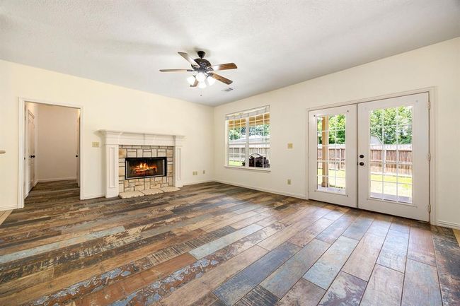 The spacious living area has abundance of natural light, wood look tile, and a fire place to keep you warm in the winter. | Image 9