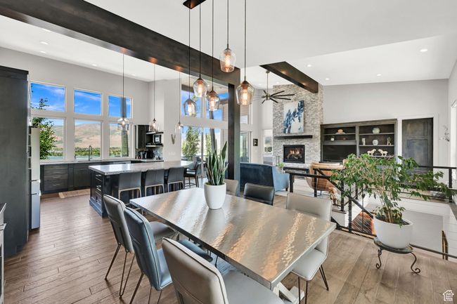 Dining area featuring a towering ceiling, recessed lighting, a ceiling fan, wood-flooring, and a fireplace | Image 26