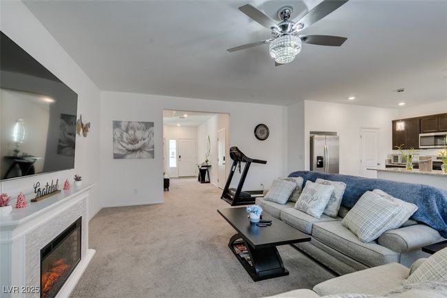 Living room with a warm lit fireplace, ceiling fan, recessed lighting, and light carpet | Image 29