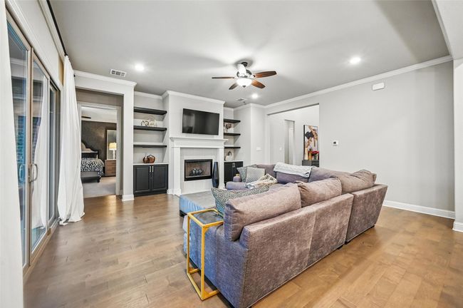 Living room with ceiling fan, light wood-style flooring, recessed lighting, a tiled fireplace, and ornamental molding | Image 14