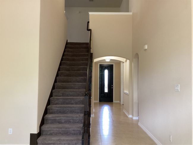 Foyer with arched walkways, stairway, light tile patterned floors, baseboards, and a towering ceiling | Image 22