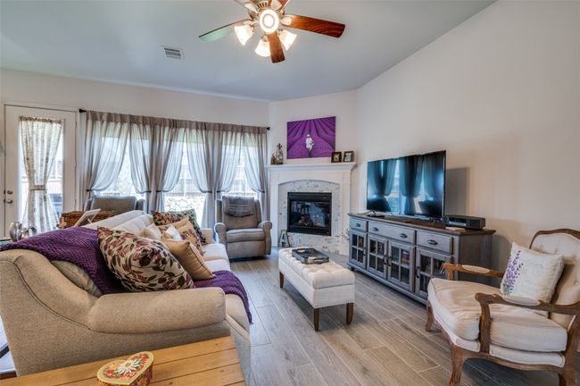 Living room featuring a ceiling fan, wood finished floors, and a glass covered fireplace | Image 9
