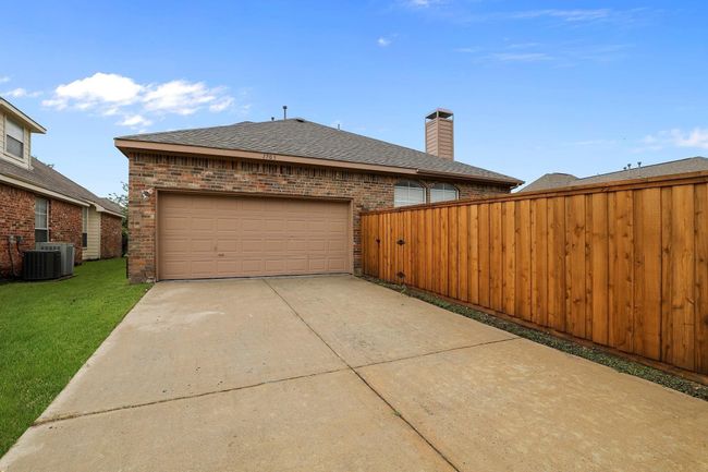View of side of home with brick siding, driveway, a garage, roof with shingles, and a chimney | Image 15