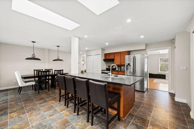 Kitchen with appliances with stainless steel finishes, dark countertops, a kitchen bar, a skylight, and a sink | Image 10