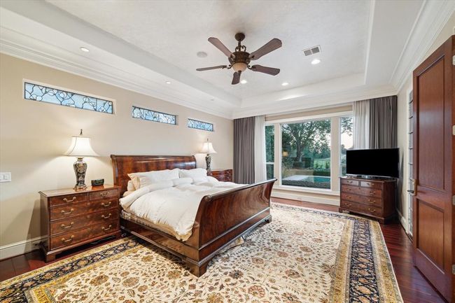 The spacious primary room is well-lit with recessed lighting and natural light from a large window offering a scenic view. There's a ceiling fan for comfort and ample storage. | Image 17