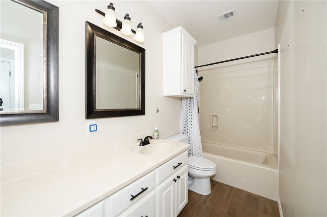 Full bath featuring visible vents, shower / bathtub combination, toilet, wood finished floors, and vanity | Image 23
