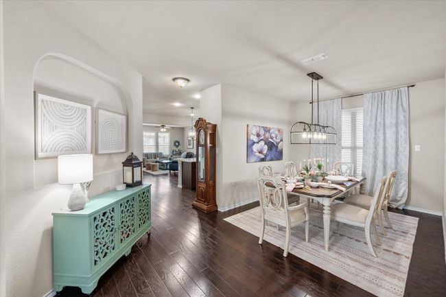 Dining room with a notable chandelier, visible vents, baseboards, and dark wood-style floors | Image 6