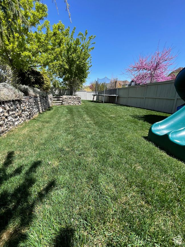 View of yard featuring a trampoline, a fenced backyard, and a playground | Image 64