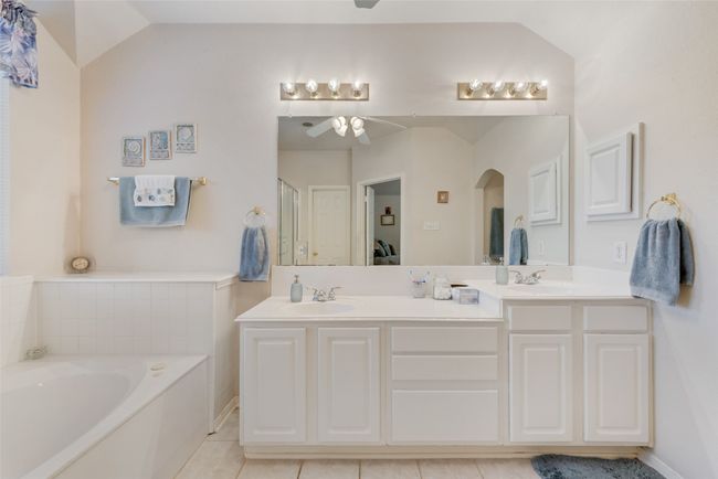 Bathroom with ceiling fan, a bath, double vanity, lofted ceiling, and tile patterned floors | Image 24