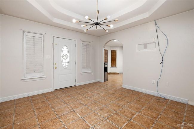 Tiled entryway featuring a notable chandelier and a raised ceiling | Image 4