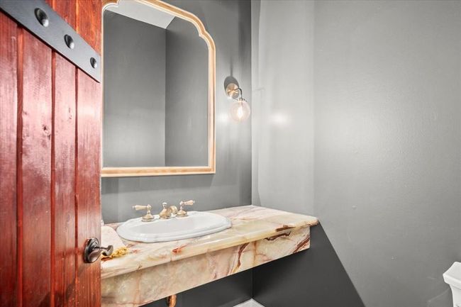his charming powder room pairs style and whimsy with a live-edge wood vanity, vessel sink, and gold-framed mirror—sure to impress your guests. | Image 20