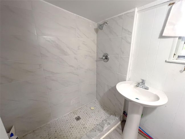 Bathroom with a tile shower and sink | Image 7