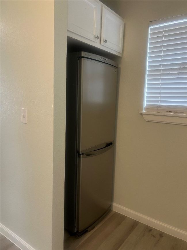 Kitchen featuring stainless steel fridge, light wood-type flooring, and white cabinets | Image 8
