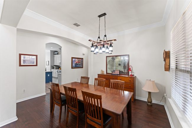 Dining area with dark wood finished floors, arched walkways, ornamental molding, and a chandelier | Image 14