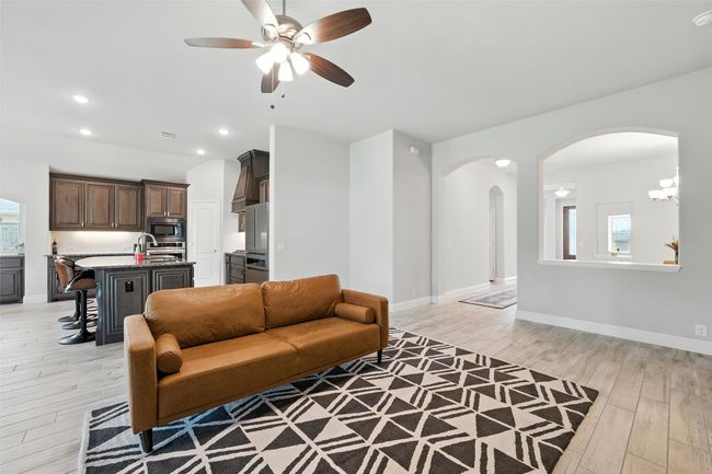 Living room featuring ceiling fan, arched walkways, light wood-style flooring, and recessed lighting | Image 10