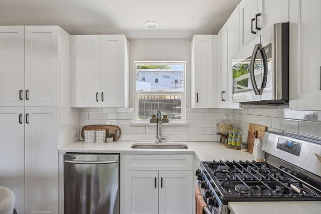 Kitchen with stainless steel appliances, light countertops, and white cabinets | Image 14