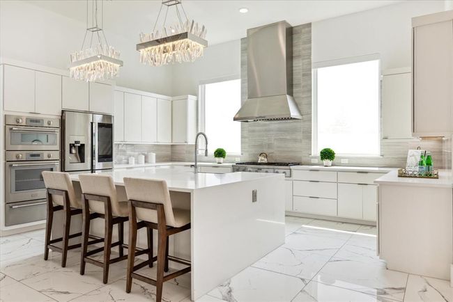 The expansive island serves as both a practical workspace and a casual dining area, perfect for entertaining guests or enjoying a quick meal. Quartz countertops and a stylish backsplash add a touch of luxury, while ample storage solutions ensure a clutter-free environment. | Image 15