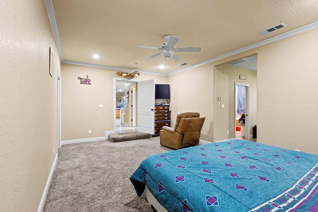 Carpeted bedroom featuring baseboards, visible vents, ceiling fan, and crown molding | Image 22