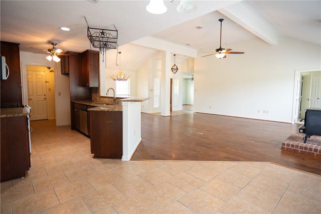 Kitchen with a ceiling fan, open floor plan, a peninsula, and dark stone countertops | Image 23