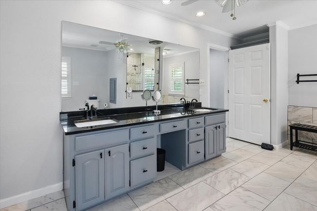 Bathroom with ceiling fan, double vanity, marble look tile flooring, crown molding, and baseboards | Image 18