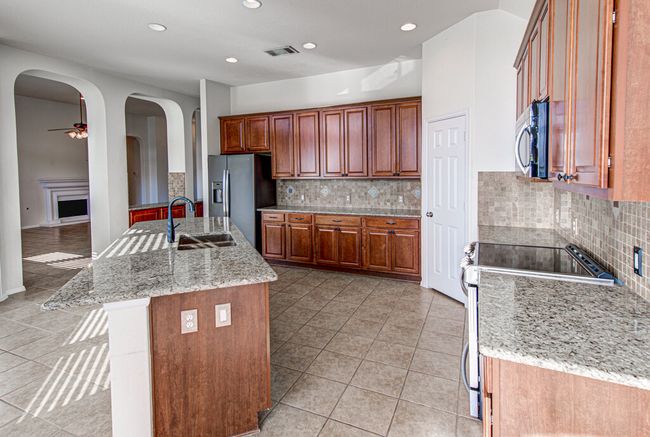 Kitchen featuring visible vents, arched walkways, ceiling fan, a sink, and appliances with stainless steel finishes | Image 15