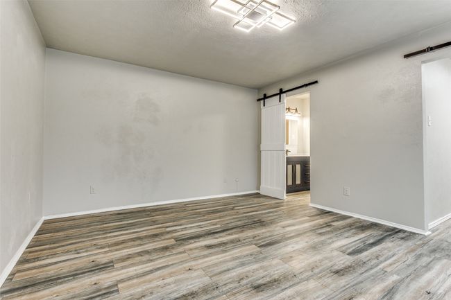 Spare room featuring a barn door, wood finished floors, and a textured ceiling | Image 19