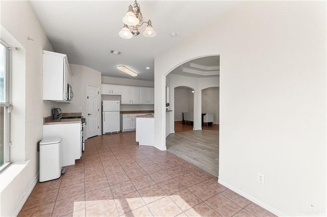 Kitchen featuring appliances with stainless steel finishes, arched walkways, a chandelier, white cabinets, and light tile patterned floors | Image 18