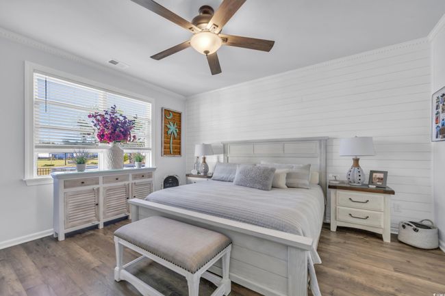 Bedroom featuring multiple windows, wood finished floors, wooden walls, and a ceiling fan | Image 22