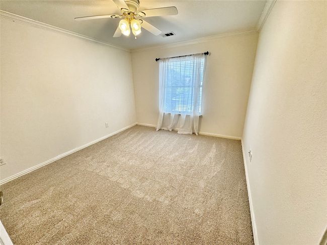 Spare room with crown molding, carpet, and a ceiling fan | Image 26