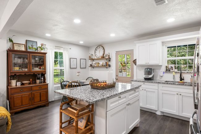 Kitchen with a kitchen bar, dark wood-style floors, healthy amount of natural light, recessed lighting, and white cabinets | Image 14
