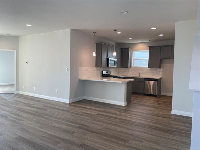 Kitchen with stainless steel appliances, a peninsula, backsplash, dark wood finished floors, and recessed lighting | Image 5