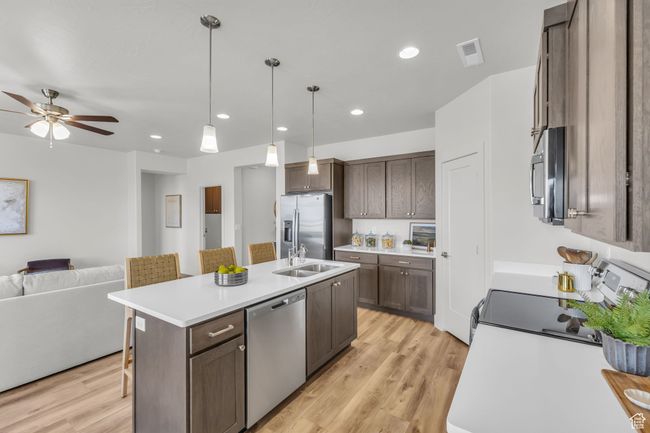 Kitchen featuring pendant lighting, a kitchen island with sink, ceiling fan, light wood-type flooring, and appliances with stainless steel finishes | Image 12