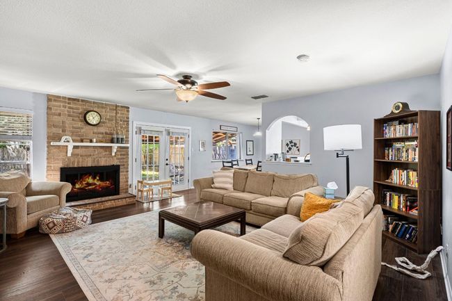 Living area featuring healthy amount of natural light, dark wood-style floors, a brick fireplace, and a ceiling fan | Image 7