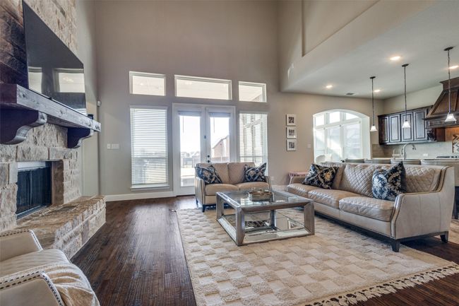 Living room featuring a towering ceiling, a fireplace, sink, hardwood / wood-style flooring, and french doors | Image 7
