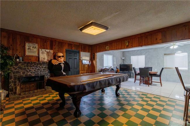 Playroom featuring wood walls, pool table, a fireplace, a textured ceiling, and ceiling fan | Image 30