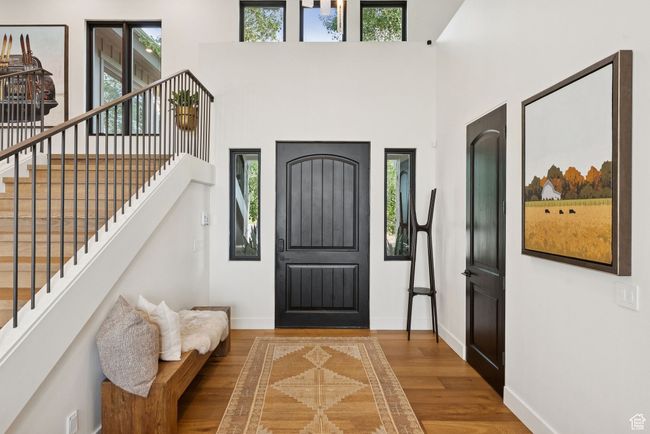 Entrance foyer featuring healthy amount of natural light, wood finished floors, stairway, and a towering ceiling | Image 64