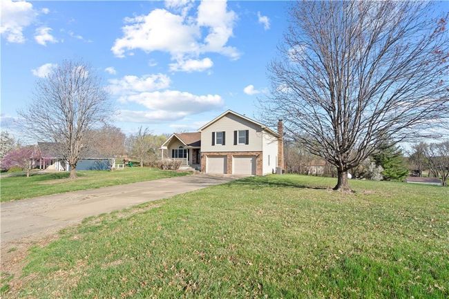 View of front of property featuring concrete driveway, a front yard, brick siding, and an attached garage | Image 26