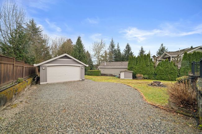 View of yard with a garage, a fire pit, an outbuilding, and fence | Image 39